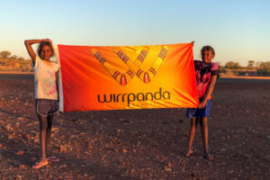 2 female children stand with wirrpanda foundation flag in remote mid west town wiluna in