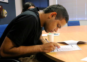 young adult male participant signing employment contract at desk