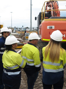group of people facing away from the camera in hard hats and high vis on a building site